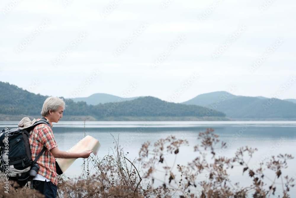 traveler hiker man with backpack hiking near lake. tourist backpacker with map relaxing in forest. travel lifestyle, summer vacation concept