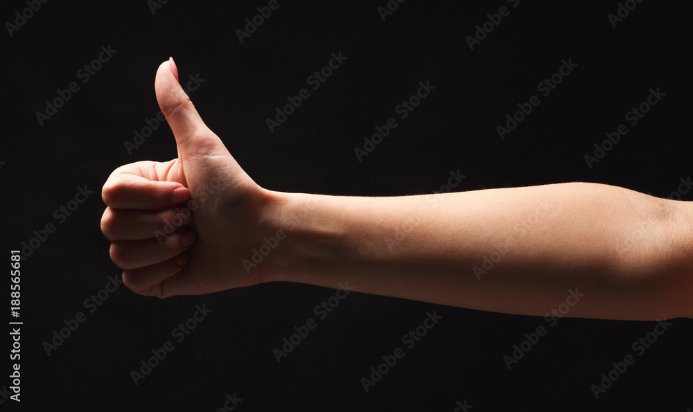 Caucasian female hand making thumb up gesture, isolated on black Caucasian female hand making thumb up gesture, isolated on black