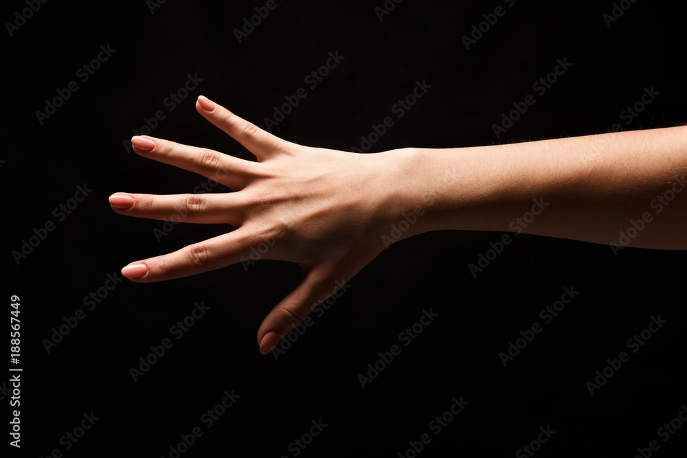 Female hand shows number five isolated at black