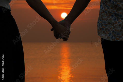 Couple holding hands and blurry beautiful sunset in background