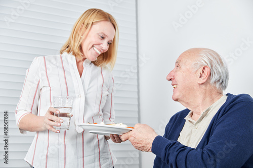 Pflegedienst Frau bringt altem Mann eine Mahlzeit