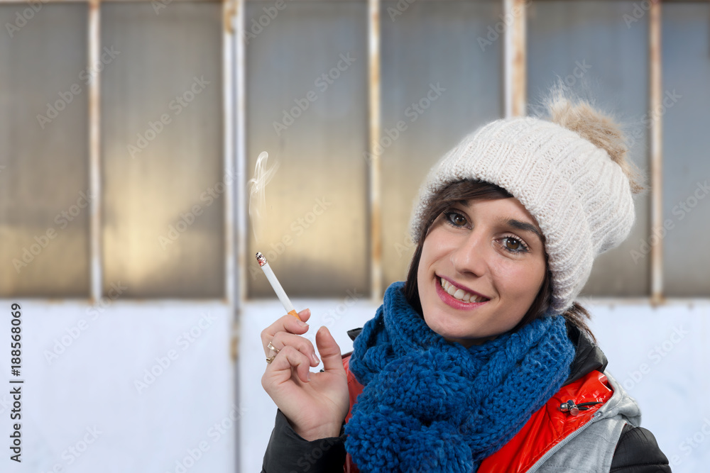 young woman with winter cap smoking a cigarette young woman with winter cap smoking a cigarette