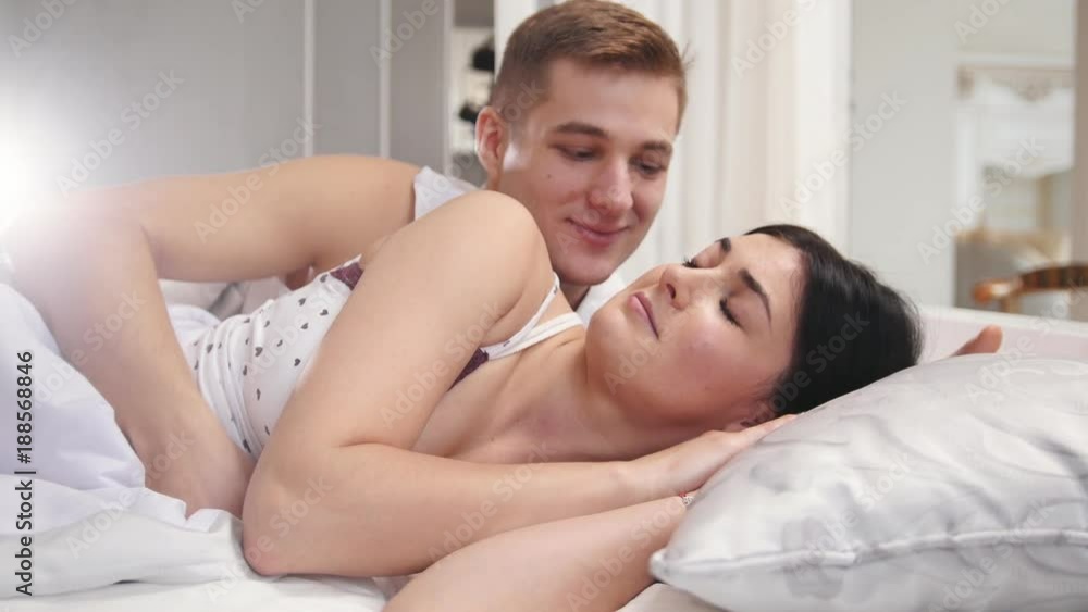 Affectionate guy waking up sleeping girl by kissing her, young couple wakes up Affectionate guy waking up sleeping girl by kissing her, young couple wakes up