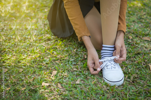 Asian young girl tying her shoelaces after walking in the park