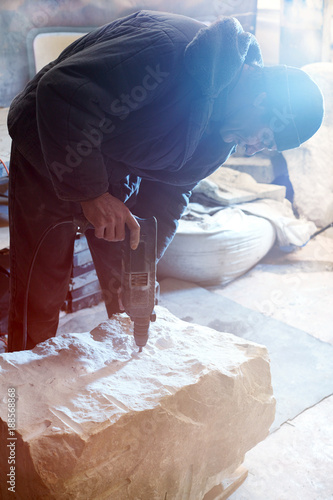 Working sculptor drills deep holes in the marble block.