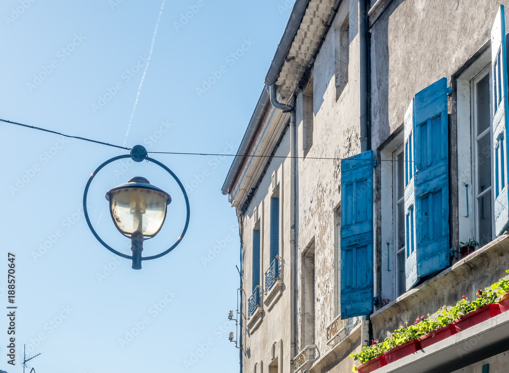 Night lantern hang over street in old classic buildings in countryside of France, under clear blue sky in daylight time Night lantern hang over street in old classic buildings in countryside of France, under clear blue sky in daylight time