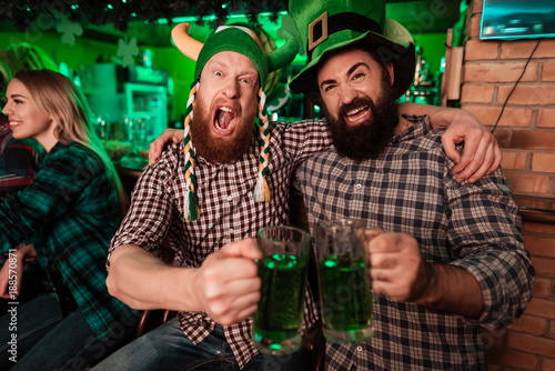 Two men in carnival caps celebrate St. Patrick's Day.