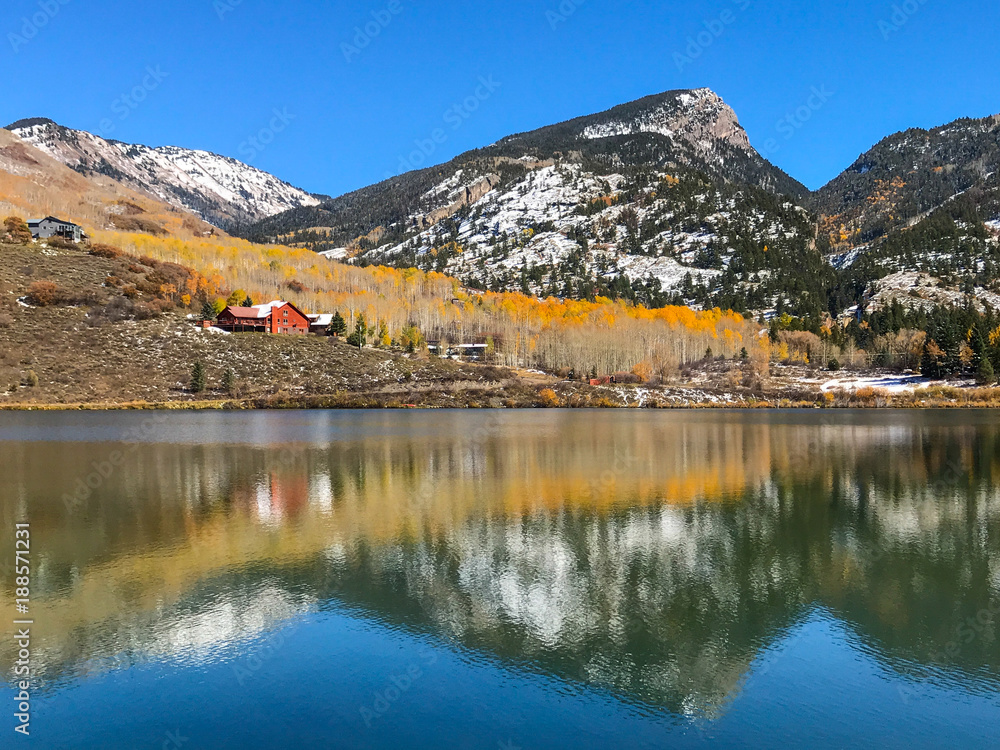 Red house in the mountains and a reflection in the lake