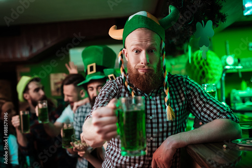 A man in a funny hat celebrates St. Patrick's Day with friends.