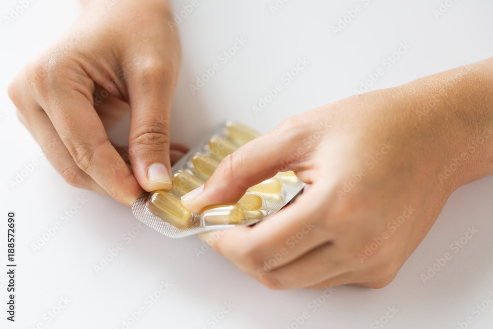 Obraz premium woman hands opening pack of medicine capsules