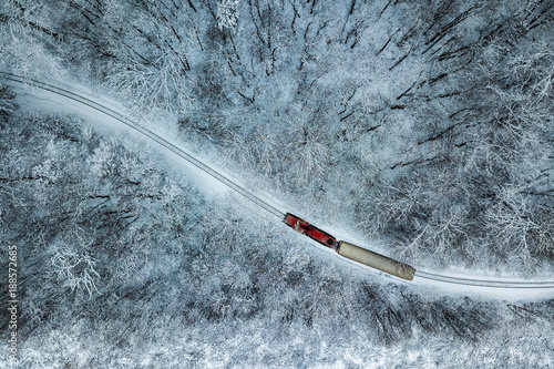 Budapest, Hungary - Aerial view of snowy forest with red train on a track at winter time, captured from above with a drone at Huvosvolgy