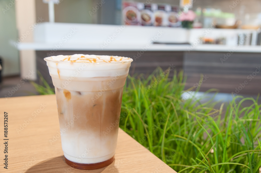 Gold caramel topping on white cream in coffee cup with green grass background. Gold caramel topping on white cream in coffee cup with green grass background.