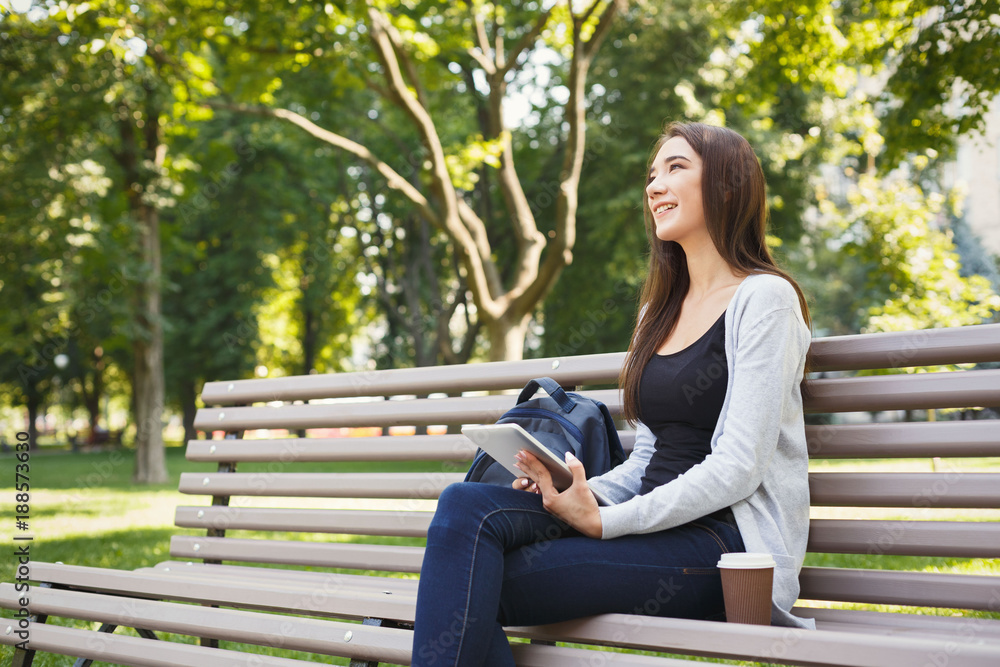 Smiling woman in park using digital tablet Smiling woman in park using digital tablet