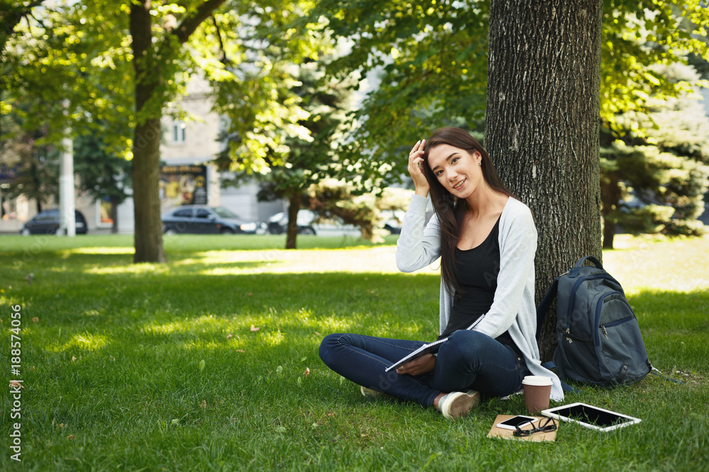 Young woman sitting with notebook on grass Young woman sitting with notebook on grass