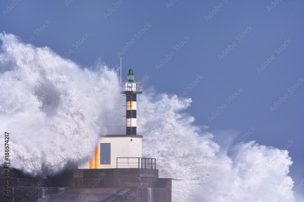 Stormy wave over lighthouse of San Esteban de Pravia.