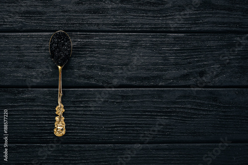 Spoon with black caviar on a wooden background. Top view. Free space for text.