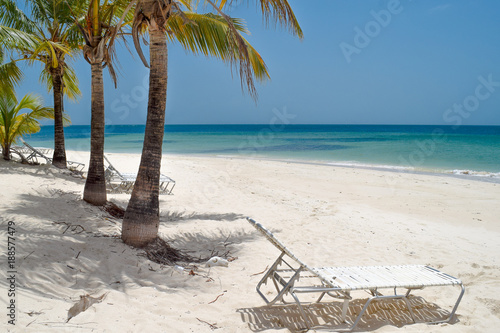Sonnenliege auf dem weißen Sandstrand in der Karibik mit Blick auf das türkis-blaue Meer 