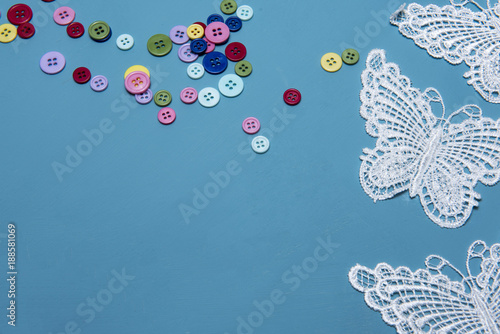 Arts and crafts background image of colourful buttons and lace butterflies, taken with copy space 