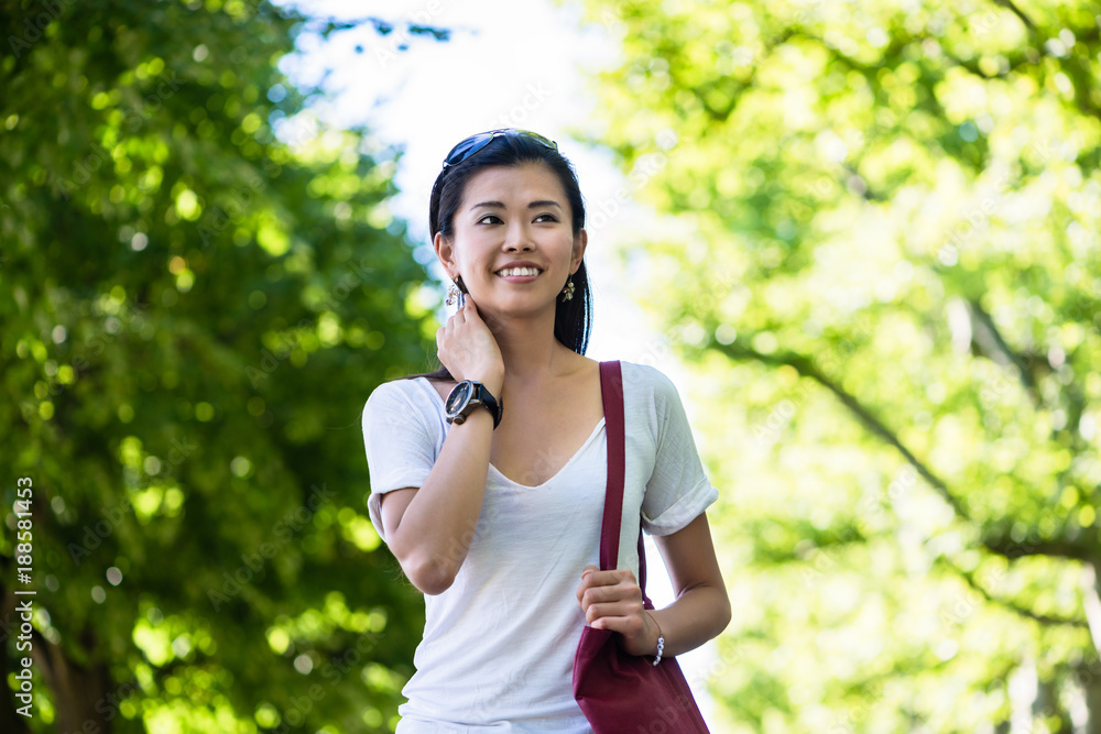 Serene beautiful young woman smiling while walking in the park in summer Serene beautiful young woman smiling while walking in the park in summer