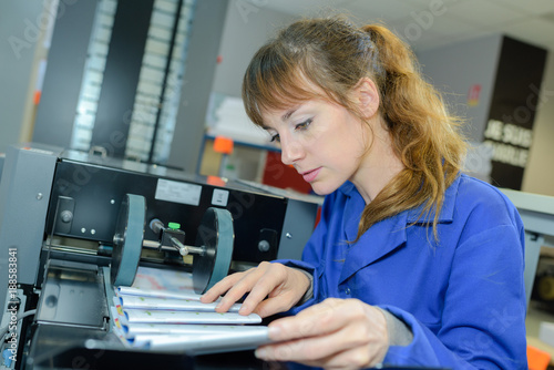 Obraz na plátne Worker checking printed matter coming off of the press