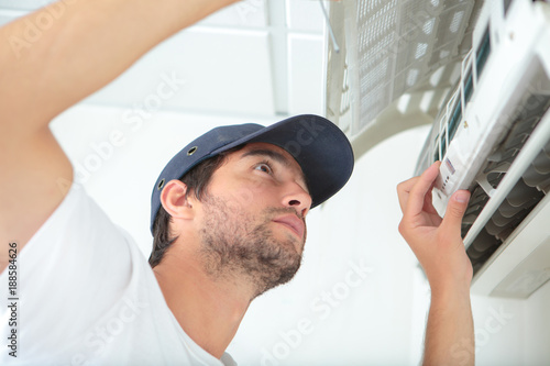 young man cleaning air conditioning system photo