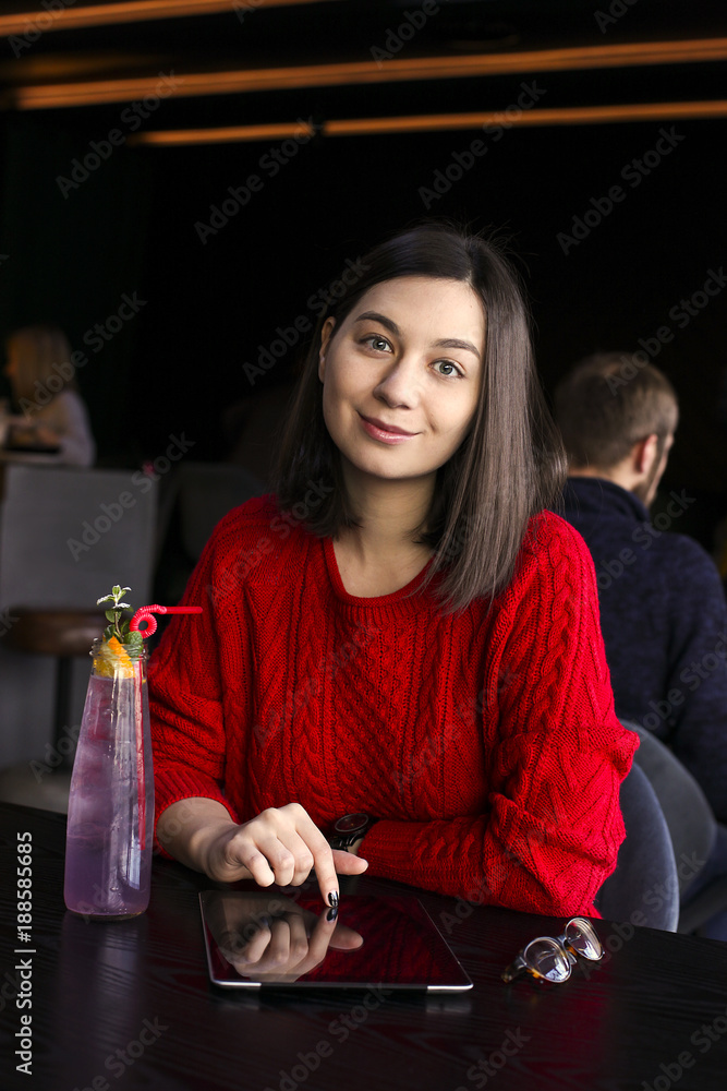 Happy young woman drinking coffee / tea and using tablet computer in a coffee shop Happy young woman drinking coffee / tea and using tablet computer in a coffee shop