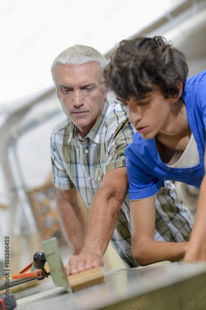 Carpenter and son using a table saw Carpenter and son using a table saw