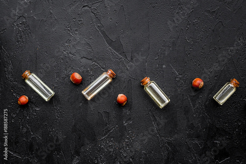 Oil for skin care. Hazelnut oil in glass bottles on black background top view copy space pattern