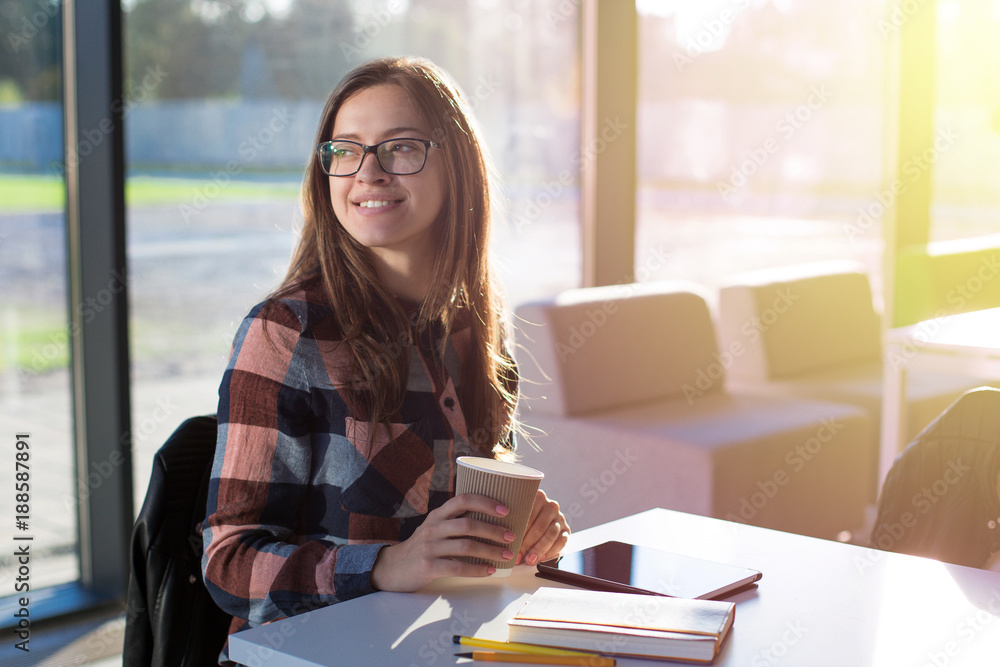 Young female girl student having coffee break in glass interior
Young female girl student having coffee break in glass interior