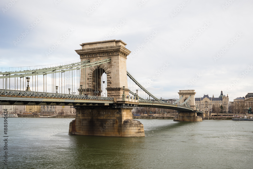 Obraz premium Chain Bridge with Danube river flowing under it as seen from riverside od Danube river in Budapest, Hungary.