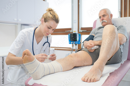 doctor bandaging seniors patients leg in hospital