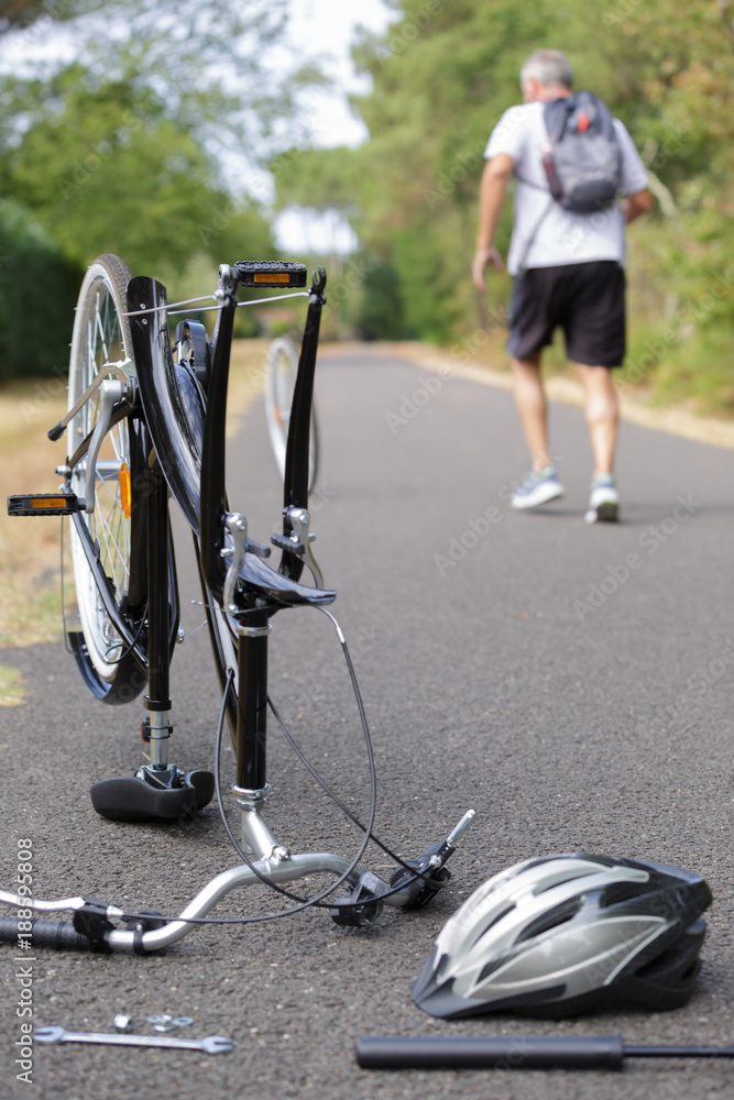 Naklejka premium Man walking off leaving broken bicycle
