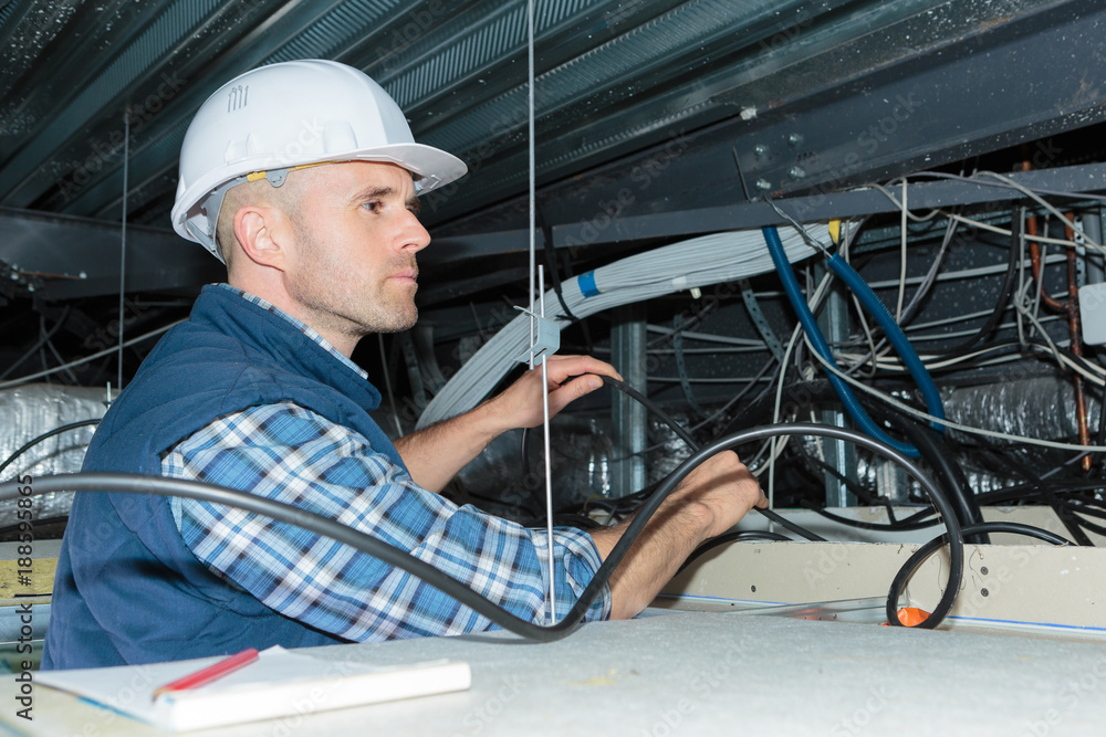 Electrician inspecting cables in roof space Electrician inspecting cables in roof space