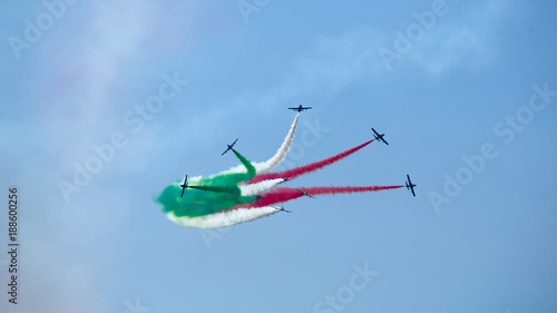 Airshow performance of Frecce Tricolori (Tricolour Arrows) with trail of italian flag colors over Grado beach, Italy.