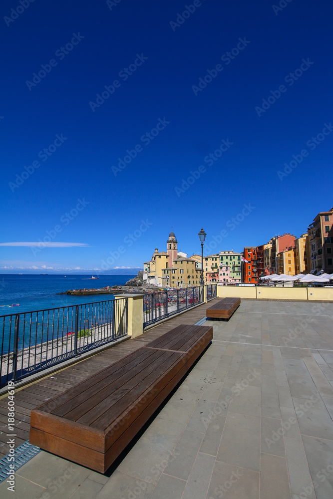 Wooden benches on the promenade and the basilica Santa Maria Assunta in Camogli, Liguria, Italy