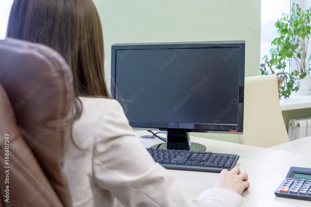 Female office worker sits in a leather chair in front of a computer and thinks Female office worker sits in a leather chair in front of a computer and thinks