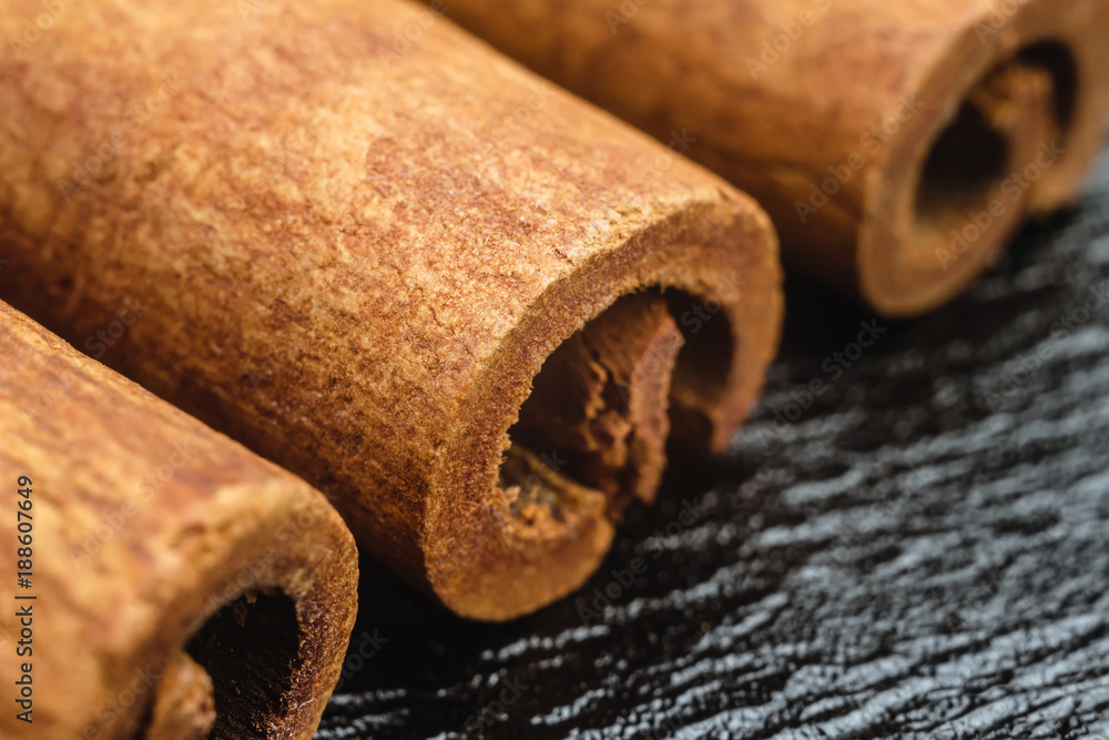 Cinnamon stick on black leather texture background, macro image Cinnamon stick on black leather texture background, macro image