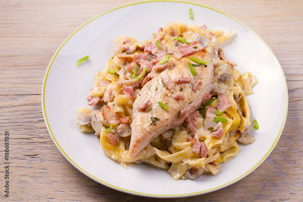 Chicken breast and egg noodles with bacon and mushrooms in creamy sauce. horizontal