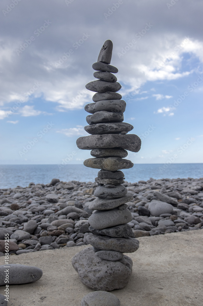 Fototapeta premium High stone cairn tower, poise stones, rock zen sculpture, light grey pebbles