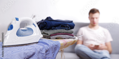 Junger Mann genervt vom Bügeln 