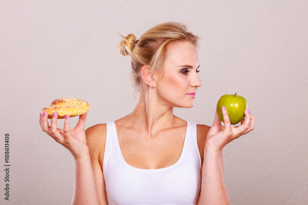 Woman holds cake and fruit in hand choosing Woman holds cake and fruit in hand choosing