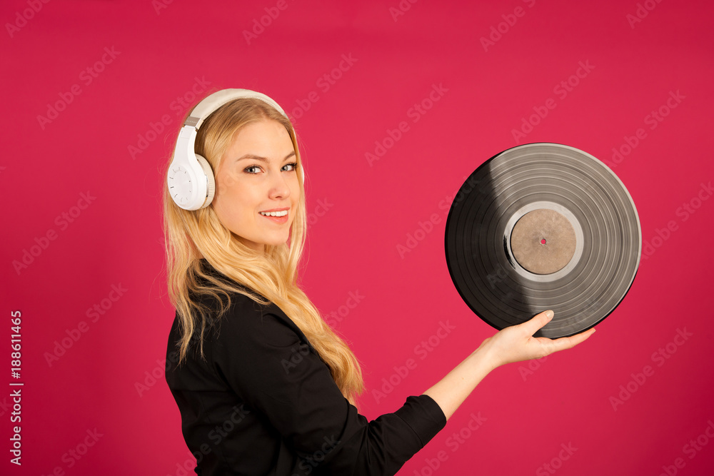 Fototapeta premium Beautiful young woman holding a vinyl in her hands as she listens to the music