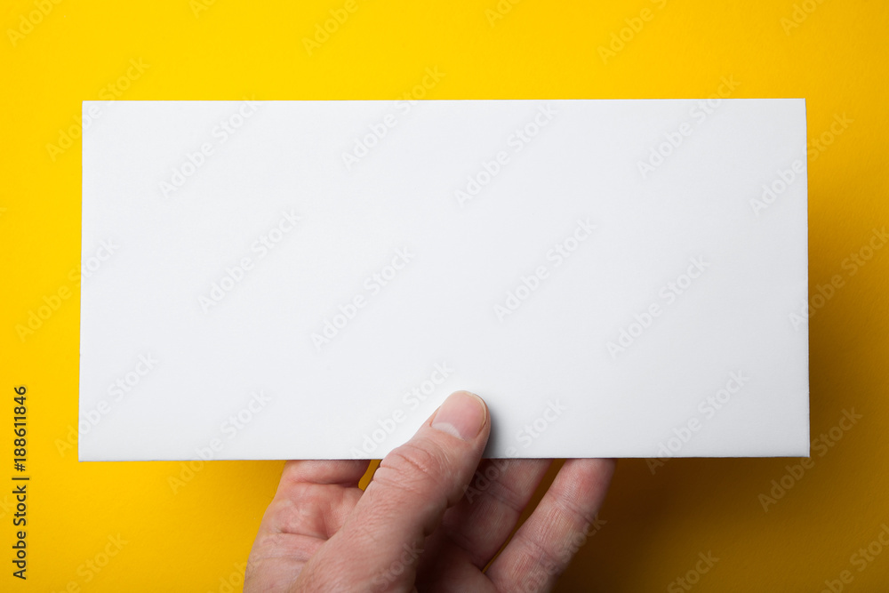 Empty white DL Flyer in hand on yellow background. Mockup, horizontal. Empty white DL Flyer in hand on yellow background. Mockup, horizontal.