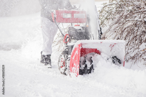 hard working man clearing snow with a snowblower machine plough tool after extreme heavy snow fall storm 