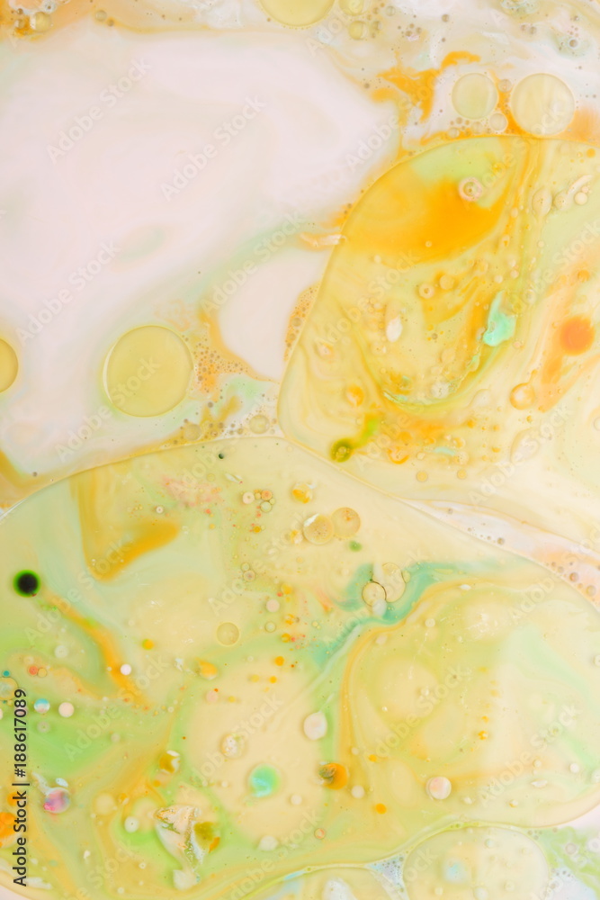 Multicolored oil drops on a liquid, abstract colored background, pop art texture, yellow circles with bright drops of paint, minimalism, pastel pattern