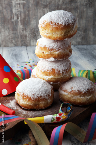 German donuts with jam and icing sugar. Carnival powdered sugar raised donuts with paper streamers.
