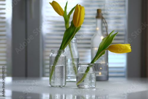 желтые тюльпаны в стеклянных банках на столе