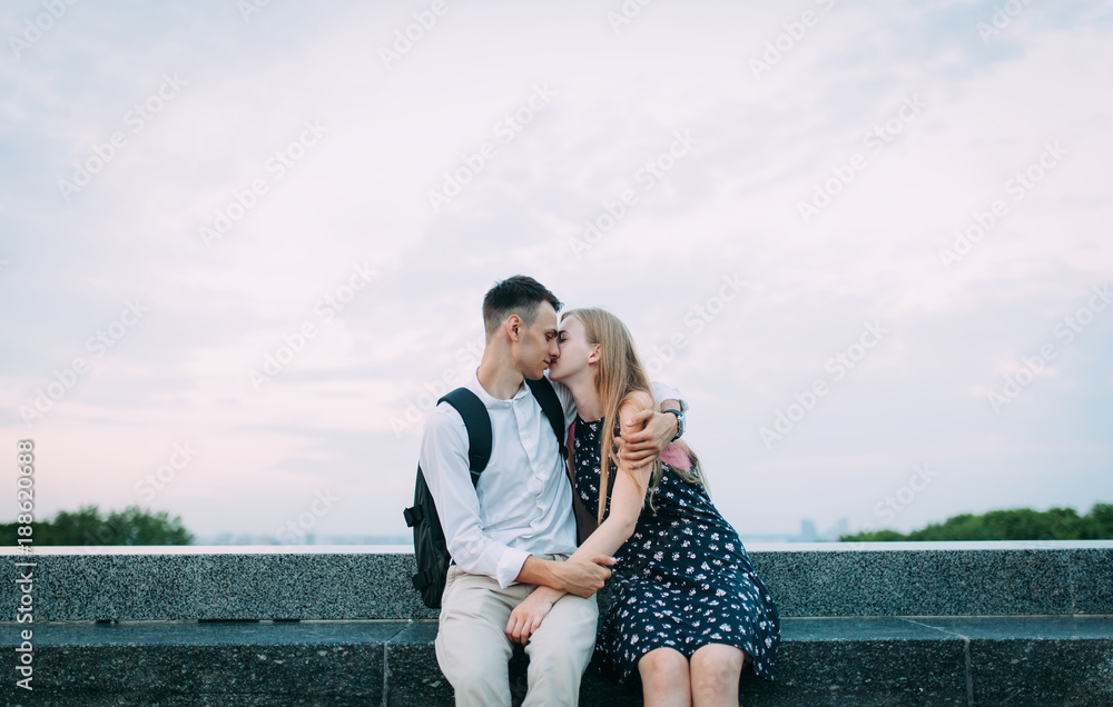 Photo of a young couple. The man in the white shirt hugging a girl in a black dress on a background of open sky. Valentine's day, Lovely tender photo perfect for advertising or banner,