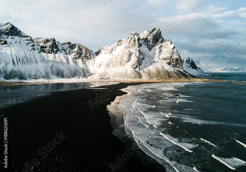 View of black sand beach with snow covered mountain in background photo
