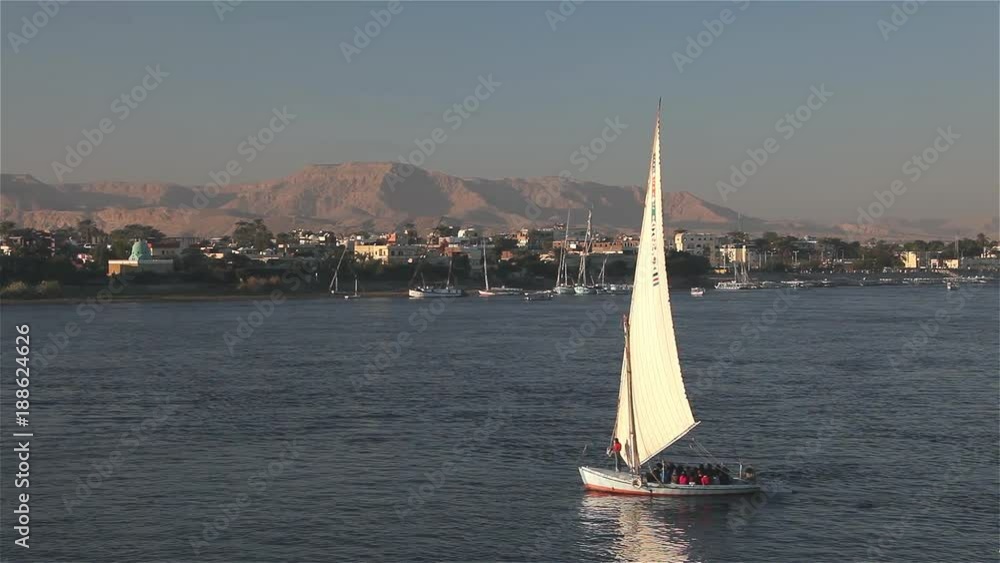 Felucca Sailing In Low Sun; River Nile Luxor; River Nile, Luxor, Egypt Felucca Sailing In Low Sun; River Nile Luxor; River Nile, Luxor, Egypt